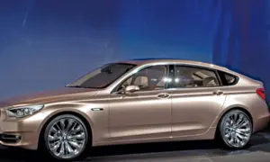 Eleganckie, złociste bmw 5gt z chromowanymi felgami prezentuje się imponująco na tle niebieskiego, świetlistego tła.