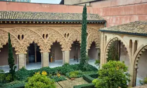 Patio de la casa de los Morlanes con arcos de yesería intrincada, vegetación exuberante y naranjos cargados de frutos.
