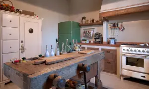 Un vecchio banco da falegname diventa un'isola cucina rustica, con taglieri e bottiglie d'olio.