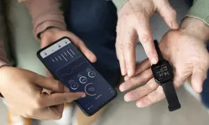 Dwie osoby analizują dane z zegarka Amazfit na smartfonie. Amazfit to firma znana z inteligentnych urządzeń do śledzenia aktywności.