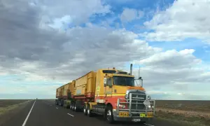 Żółty road train pędzi przez pustkowie. Zastanawiasz się, ile zarabia kierowca tira?