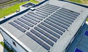 Duży płaski dach pokryty panelami fotowoltaicznymi, które zbierają energię słoneczną.