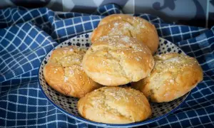 Petits pains à burger dorés et moelleux, saupoudrés de graines de sésame, dans une assiette décorée.