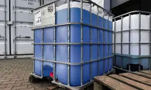Duże kontenery IBC z niebieskim płynem, prawdopodobnie glikol etylenowy, czekają na transport. Właściwości glikolu etylenowego czynią go użytecznym w wielu zastosowaniach.