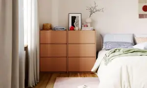 Kleines Schlafzimmer mit viel Stauraum dank zweier Kommoden. Ein Bett mit Kissen und Decke, ein Teppich und Vorhänge vervollständigen den Raum.
