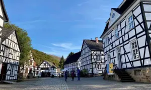 Fachwerkhäuser in einem Freilichtmuseum, das zeigt, was ist ein Freilichtmuseum. Besucher schlendern über Kopfsteinpflaster.