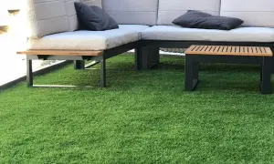 Sofá moderno y mesa auxiliar sobre césped artificial. ¿Cuánto cuesta poner césped natural?