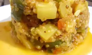 Un délicieux risotto de quinoa aux légumes verts et tomates, servi dans une sauce dorée.