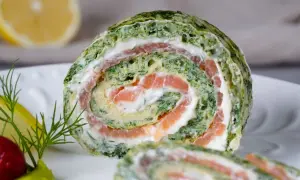 Ein saftiger Spinat Lachs Rolle auf einem Teller, garniert mit Dill und Zitrone.