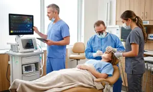 Zespół medyczny monitoruje pacjentkę podczas zabiegu stomatologicznego z zastosowaniem sedacji.