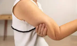 En person håller om sin armbåge, som om det gör ont i båda armarna.