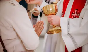 Kapłan podaje kielich podczas komunii. Czy po spowiedzi trzeba przyjąć komunię? To ważny moment duchowy.