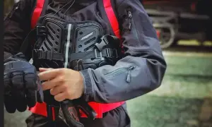 Motocyklista zakłada ochraniacz klatki piersiowej i rękawice. Różne rodzaje ochraniaczy zapewniają bezpieczeństwo.
