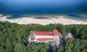 Widok z lotu ptaka na resort spa plaza otoczony lasem, z plażą i morzem w tle.