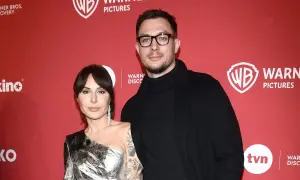 Blanka Lipińska z partnerem na czerwonym tle z logo Warner Bros. Pictures.