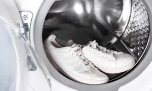 Weiße Sneaker warten im Inneren einer Waschmaschine auf ihren Einsatz.