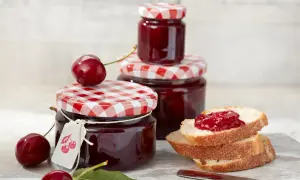 Gläser mit kirsch marmelade, frische Kirschen und Brot mit Marmelade.