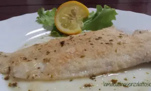 Sogliola al forno con panatura croccante, guarnita con una fetta di limone e insalata fresca. Un piatto leggero e gustoso.