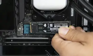 Dłoń instaluje dysk M.2 PCIe na płycie głównej komputera.