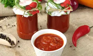 Domowy ketchup z cukinii w słoikach, miseczce i z papryczką chili.