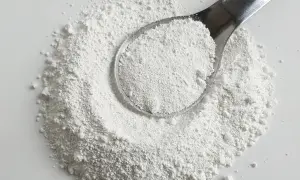 Biały proszek na łyżce i rozsypany na powierzchni. Czy to potencjalna **titanium dioxide szkodliwość**?