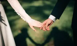 Dłonie nowożeńców splecione w uścisku, z pierścionkiem na palcu panny młodej. Zastanawiasz się, ile daje się na wesele?