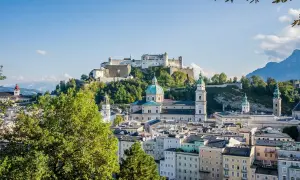 Widok na zamek Hohensalzburg i katedrę w Salzburgu, serce ziemi salzburskiej, z zielonymi drzewami w tle.
