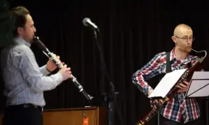 Dwóch muzyków gra na instrumentach dętych. Jeden na klarnecie, drugi na fagocie. Przed nimi stoją nuty na klarnet znane piosenki.