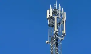 Wieża telekomunikacyjna z antenami LTE na tle błękitnego nieba.