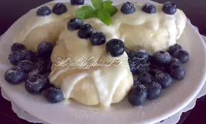 Puszyste pierogi drożdżowe polane śmietaną, ozdobione borówkami i listkiem mięty. Pyszny deser.