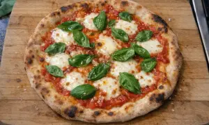 En hemmagjord pizza med tomatsås, mozzarella och färsk basilika. Ett perfekt pizza recept för en mysig kväll.