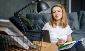 Kobieta uczy się w domu, notując w zeszycie. To idealny moment, by zgłębiać wiedzę, gdy czujemy się wypoczęci i skupieni.