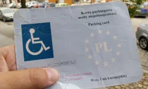 Karta parkingowa dla niepełnosprawnych, z symbolem wózka inwalidzkiego i oznaczeniem PL. Dokument wydany w Sieradzu, wzór Unii Europejskiej.