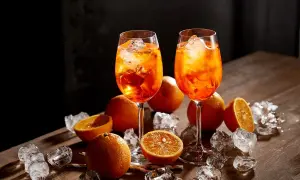 Dwa kieliszki Aperol Spritz, pomarańcze i lód na drewnianym stole. Aperol co to? Orzeźwiający drink na lato.