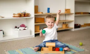 Wesoły, nadpobudliwe dziecko 2 lata bawi się kolorowymi kulkami na dywanie.