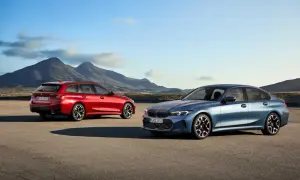Dwa nowe BMW Serii 3 2025: niebieski sedan i czerwone kombi, stoją na pustkowiu z górami w tle.