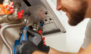 Tecnico con guanti ripara la caldaia che non si accende quando apro l'acqua calda.
