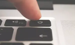Palec naciska przycisk zasilania, planując automatyczne wyłączanie komputera Windows 10.