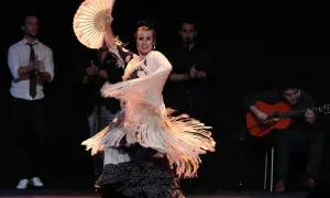 Bailaora con abanico y mantón, evocando el espíritu de Lorca y el flamenco, acompañada por guitarrista y palmeros.