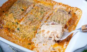 Saftiges Lachsfilet in cremiger Sahnesauce, ein köstliches Lachs Sahne Gratin, wird mit einer Gabel herausgehoben.