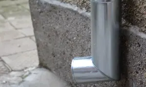 Metallenes Fallrohr an einer Betonwand. Regelmäßige dachrinnenreinigung ist wichtig, um Schäden zu vermeiden und die Nebenkosten niedrig zu halten.