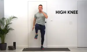 Mężczyzna wykonuje ćwiczenie high knees na macie treningowej.