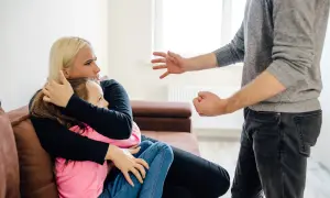 Kobieta chroni córkę przed agresywnym mężczyzną. Groźby karalne mogą prowadzić do poważnych konsekwencji prawnych.