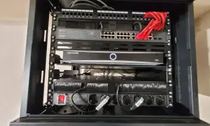 W szafie sieciowej znajduje się router, switch TP-Link, rejestrator Hikvision i listwa zasilająca.
