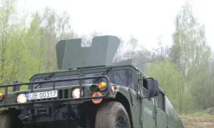 Zielony humvee z tablicą rejestracyjną UB 00317 jedzie przez las.