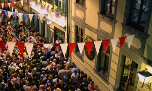 Buntes Treiben beim Bamberger Volksfest. Girlanden schmücken die Gasse, Menschenmassen feiern ausgelassen.