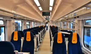 Wnętrze nowoczesnego wagonu PKP Intercity, idealnego na podróż z Poznania do Mielna. Siedzenia w kolorze granatowym z pomarańczowymi zagłówkami.