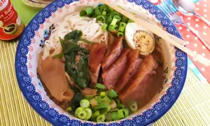 Aromaticzny ramen z kaczki z makaronem ryżowym, jajkiem na twardo, szpinakiem i szczypiorkiem.