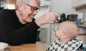 Glad mormor matar bebis med smakportioner. Första maten för en 4 månader gammal bebis.