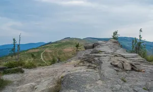Kamienista ścieżka prowadzi przez zielone zbocza, ukazując malownicze beskid śląski szczyty.